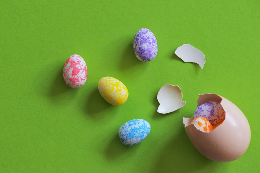 Colourful Easter eggs on green background for article on animal-friendly activities this Easter including ethical egg consumption