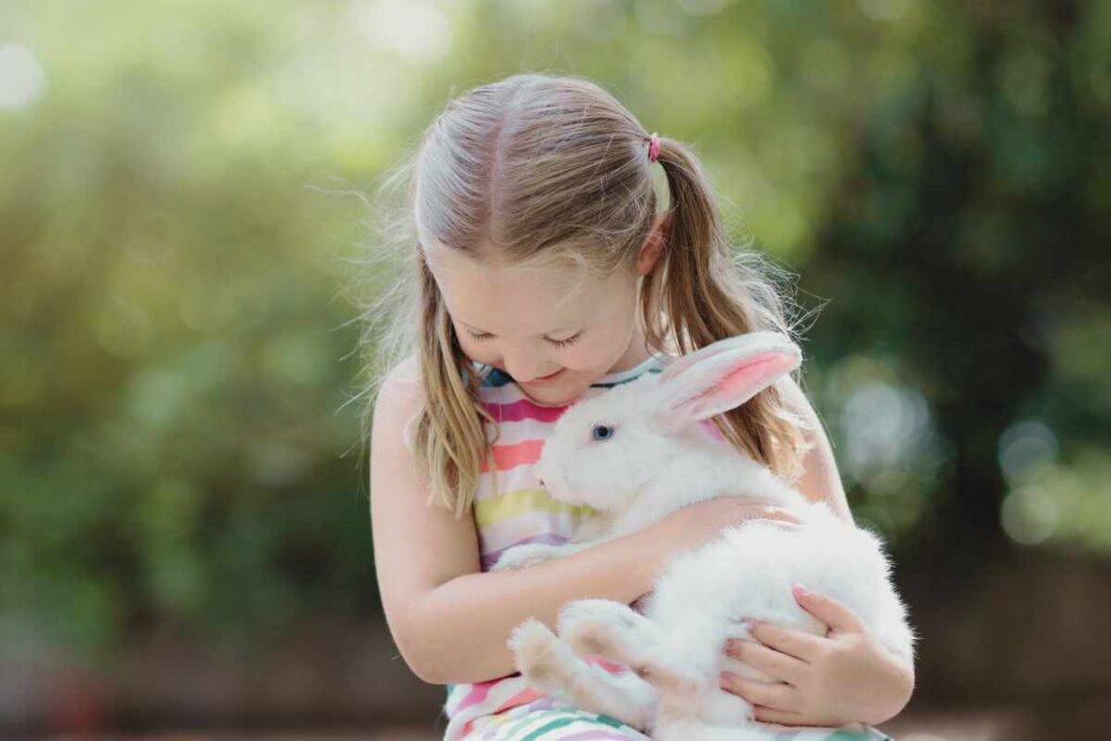 Girl with pet rabbit for pet-safe Easter and how to enjoy animal-friendly activities and ethical egg consumption.