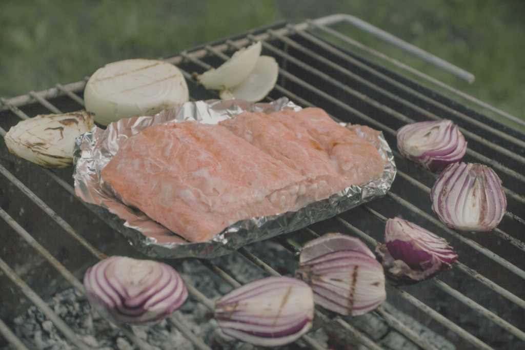 a piece of fish in foil on a bbq with onions cooking for pescatarian